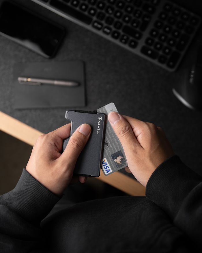 services-09 A close-up of hands holding a sleek minimalist metal wallet containing ID and credit card.