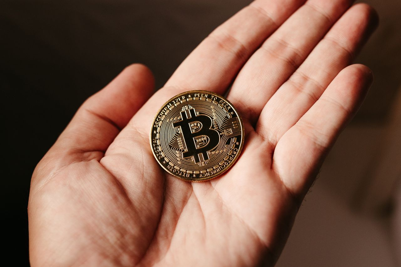 services-05 Close-up of a hand holding a Bitcoin coin, illustrating cryptocurrency concept.