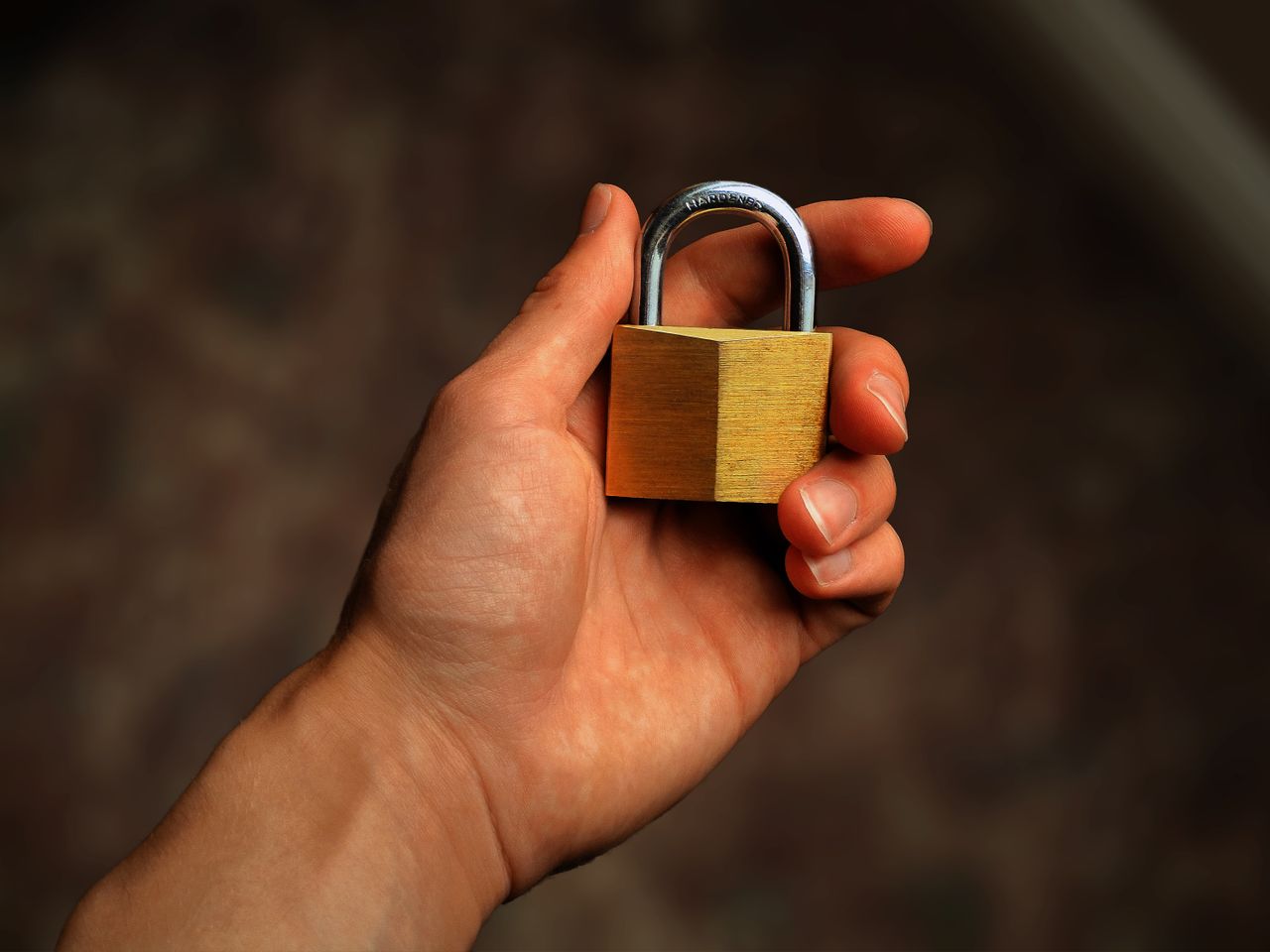 services-09 Hand holding a brass padlock, symbolizing security and protection
